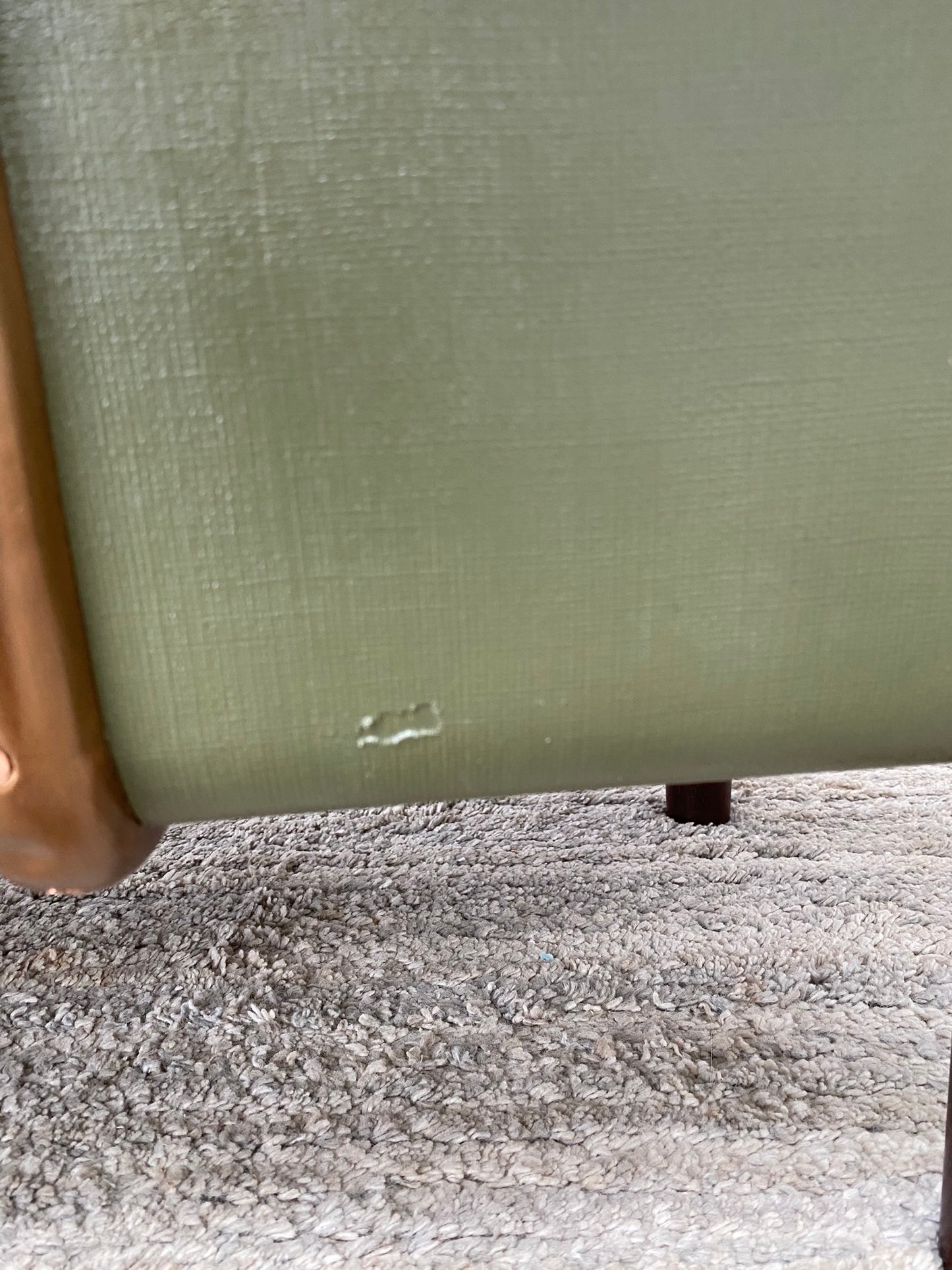 Close-up of a green upholstered chair with a visible scratch on the body.